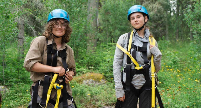 Two people wearing safety gear pose for a photo in a green wooded area. 